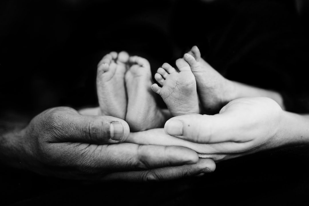 Twin newborn feet held in adult hands